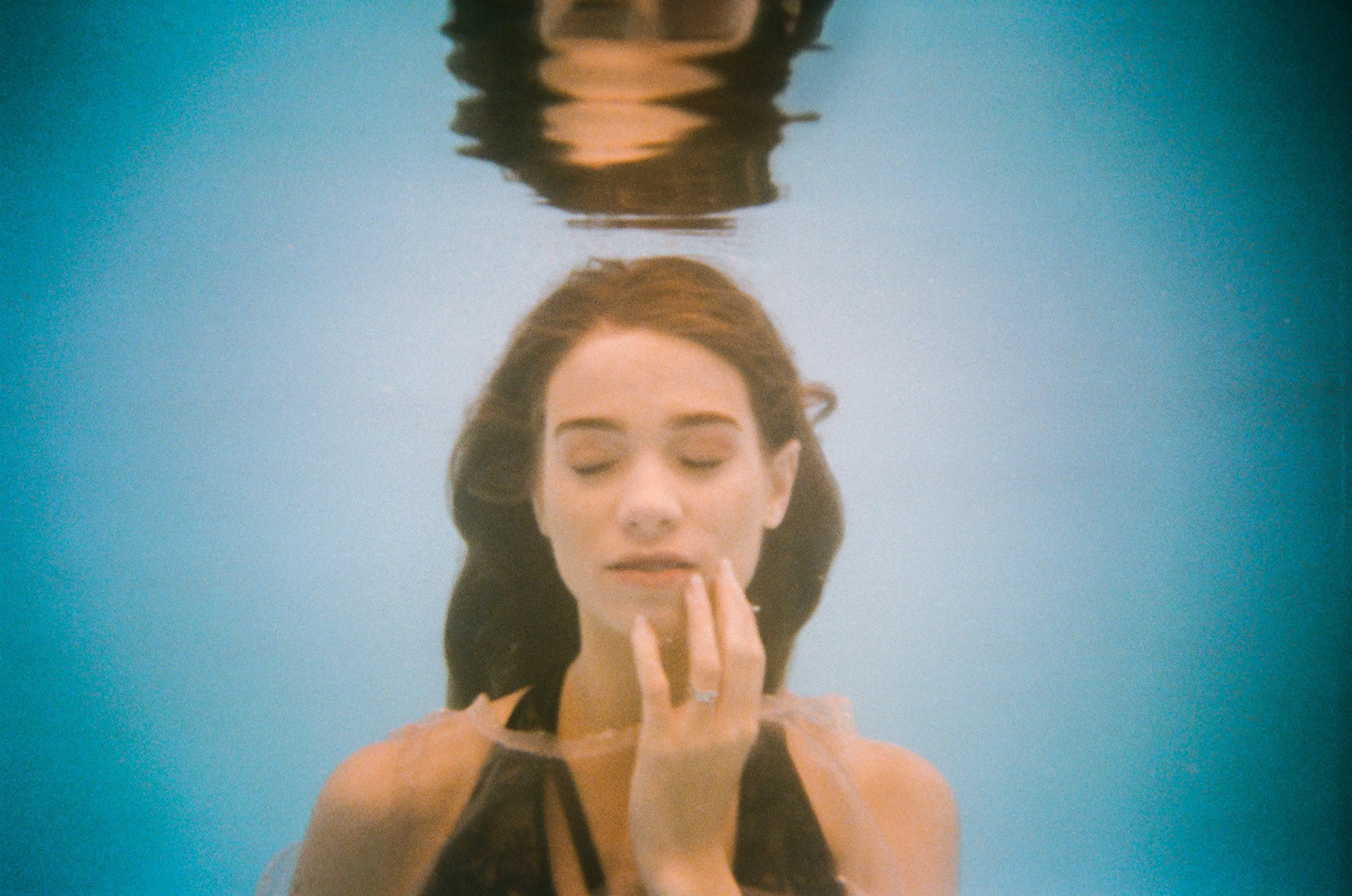 Blue underwater portrait with hands near the reflected surface