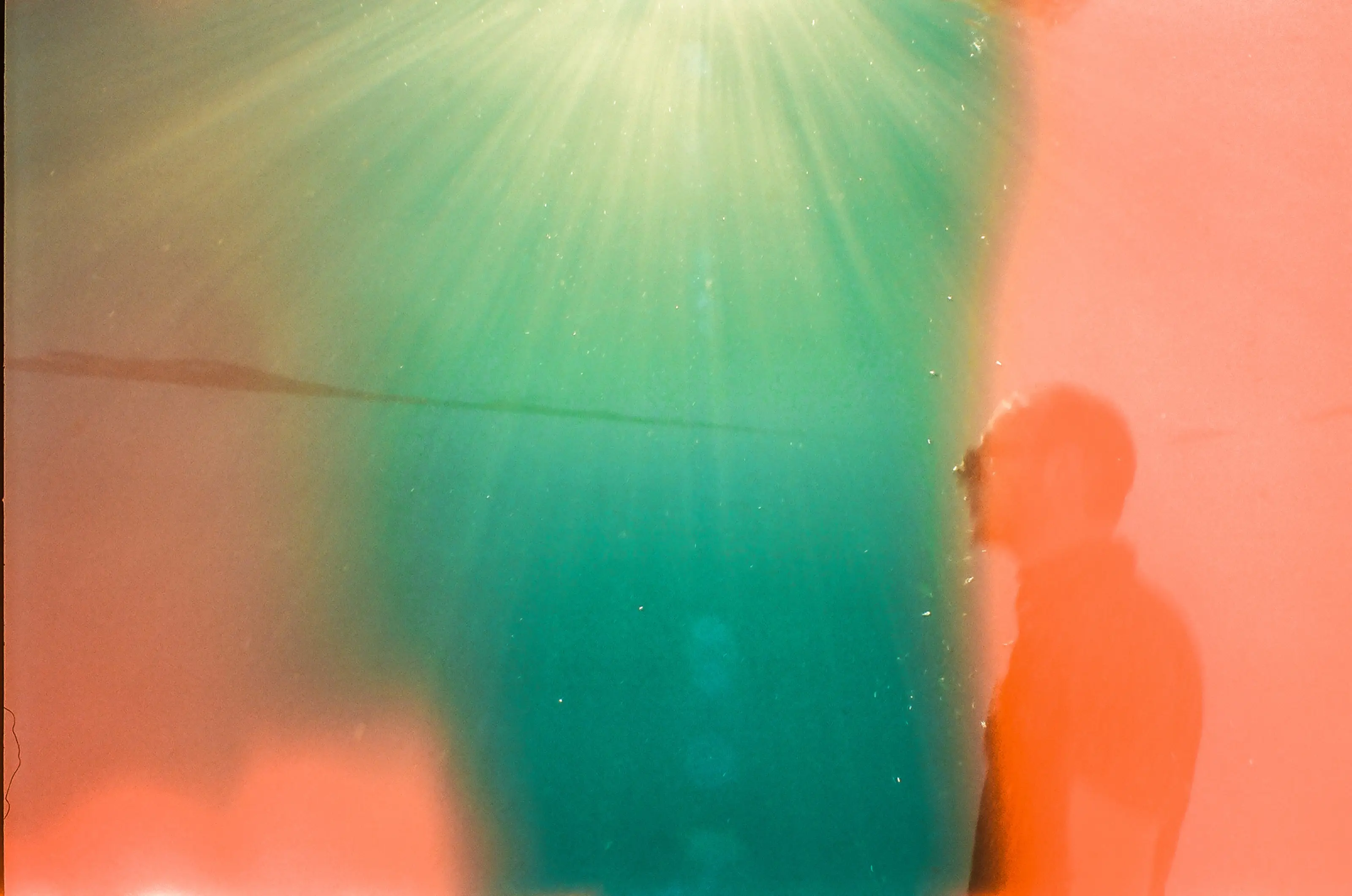 Abstract silhouette moving through deep teal water