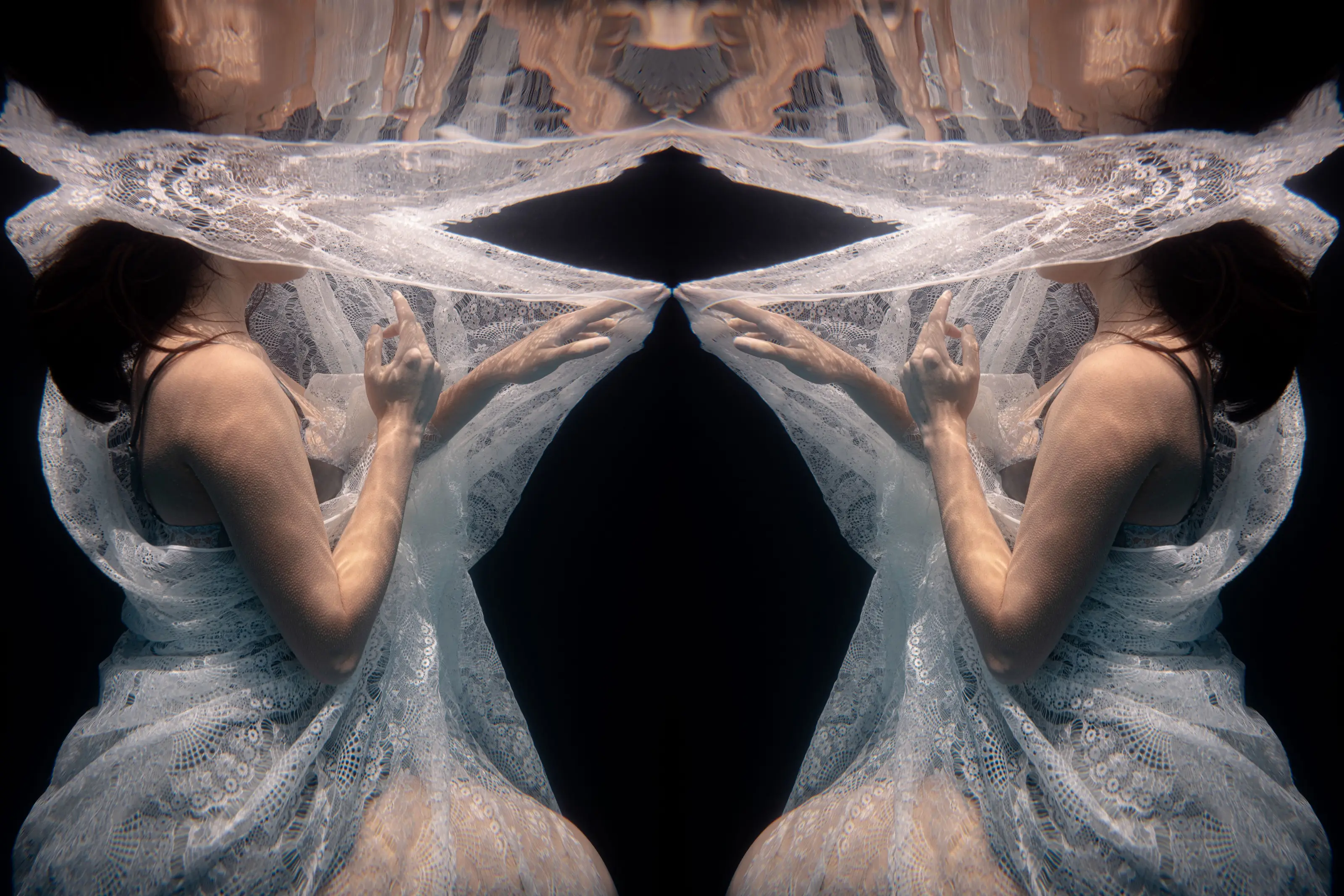 Mirrored figure wrapped in pale fabric underwater