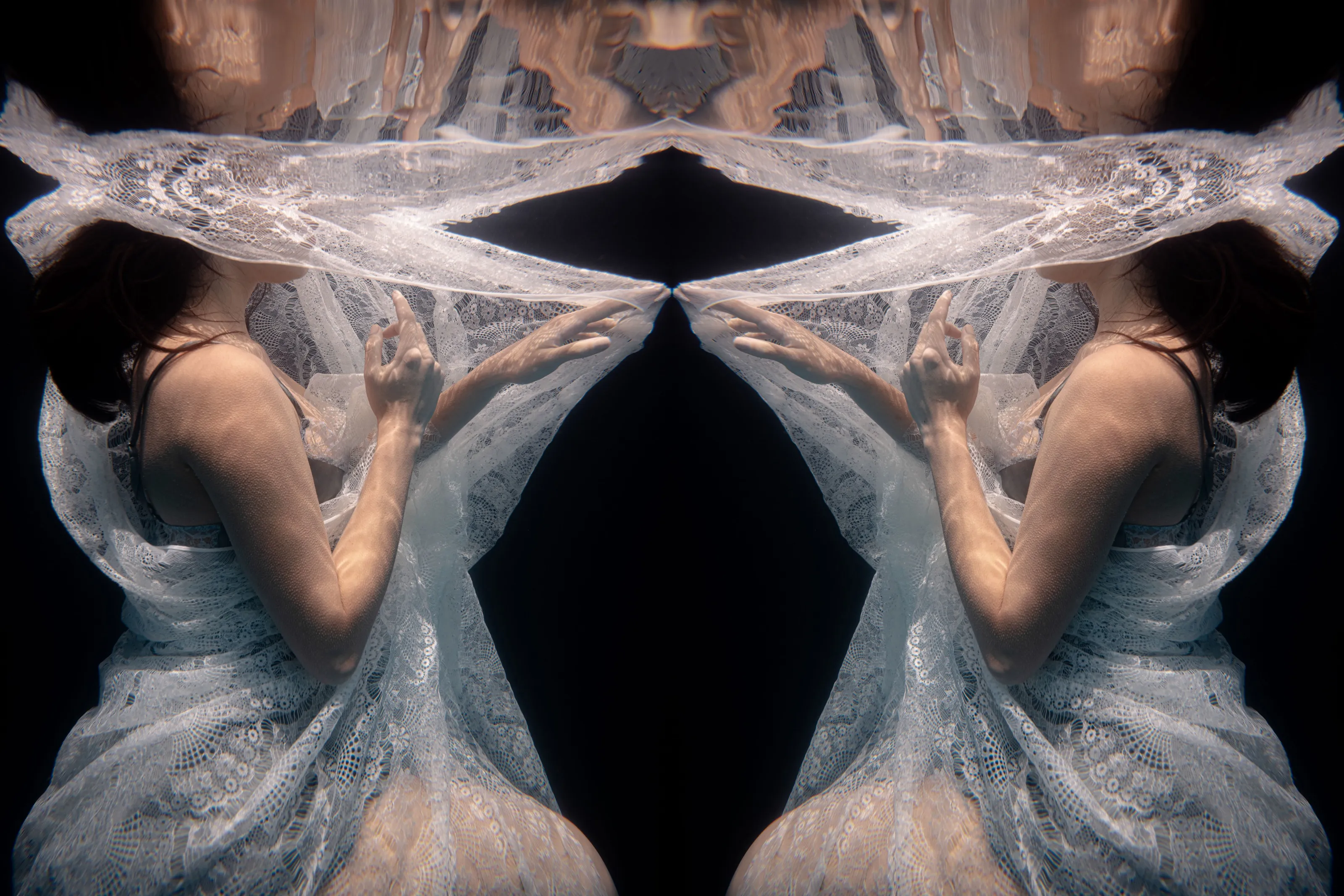 Mirrored figure wrapped in pale fabric underwater