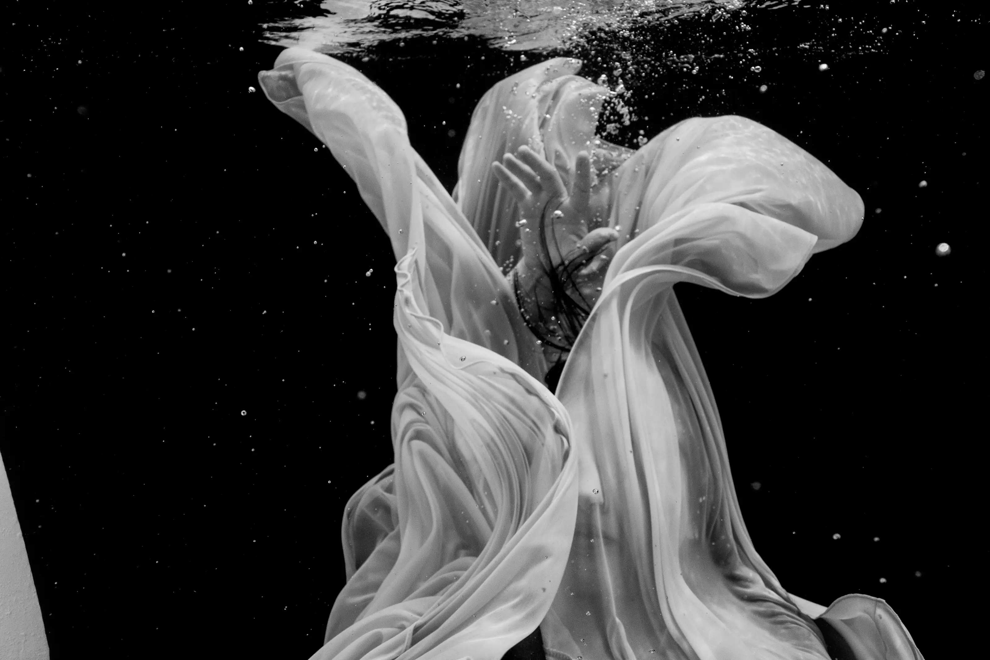 Black-and-white portrait enveloped by flowing fabric